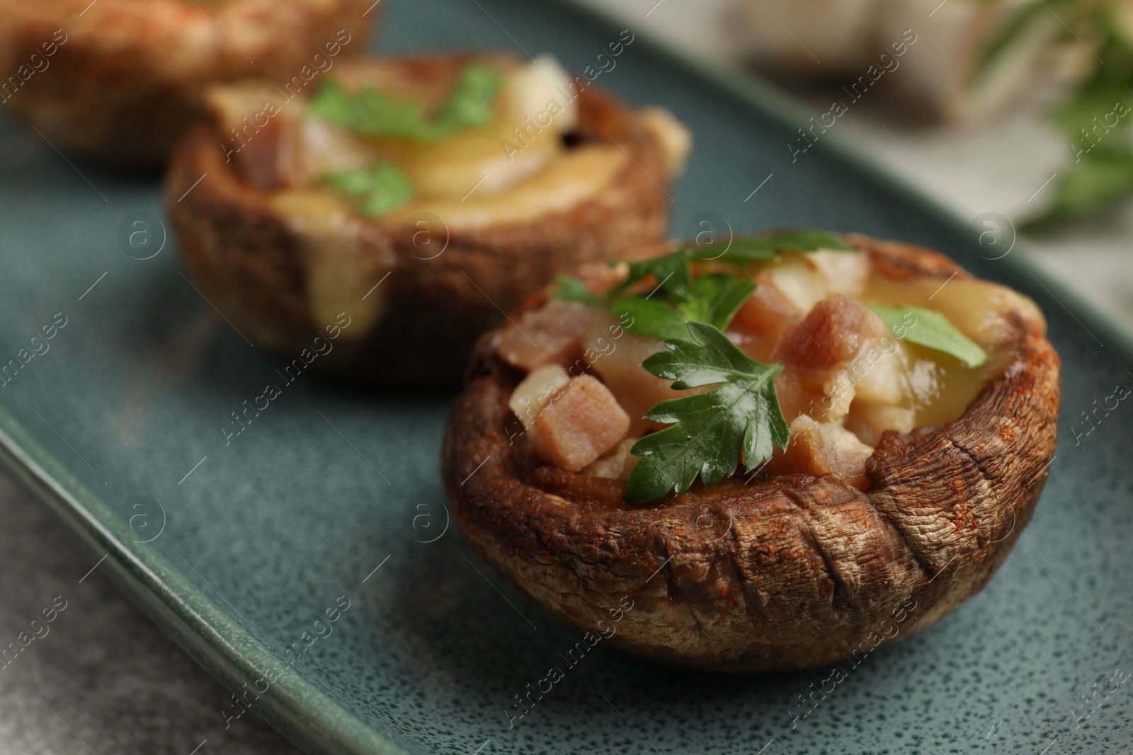 Delicious stuffed mushrooms with melted cheese and parsley on grey textured table, closeup Photo of Delicious stuffed mushrooms with melted cheese and parsley on grey textured table, closeup