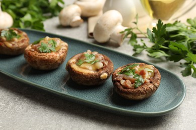 Photo of Delicious stuffed mushrooms with melted cheese and parsley on grey textured table, closeup