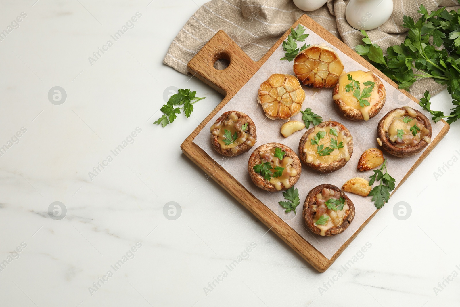 Delicious stuffed mushrooms with melted cheese, garlic and parsley on white marble table, flat lay. Space for text Photo of Delicious stuffed mushrooms with melted cheese, garlic and parsley on white marble table, flat lay. Space for text