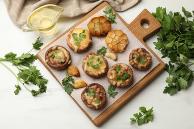 Photo of Delicious stuffed mushrooms with melted cheese, garlic and parsley on white table, flat lay