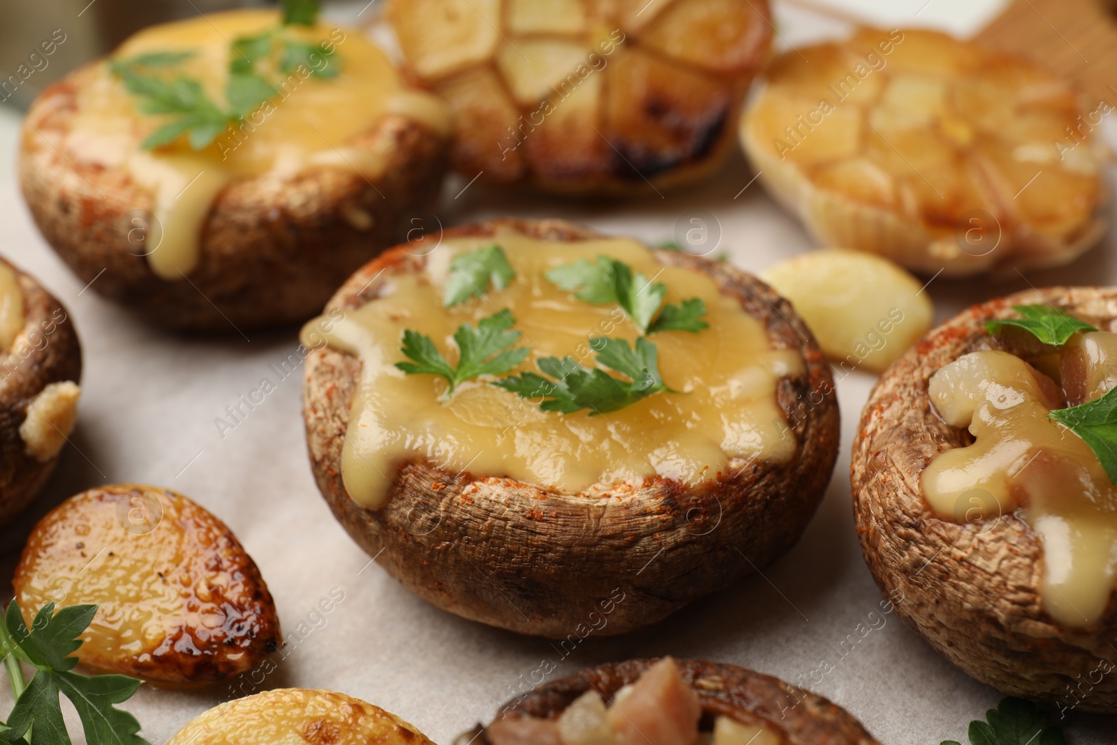 Delicious stuffed mushrooms with melted cheese and parsley on baking paper, closeup Photo of Delicious stuffed mushrooms with melted cheese and parsley on baking paper, closeup