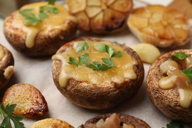Photo of Delicious stuffed mushrooms with melted cheese and parsley on baking paper, closeup