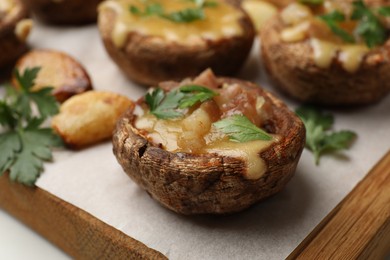 Photo of Delicious stuffed mushrooms with melted cheese and parsley on white table, closeup