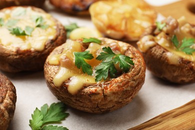 Photo of Delicious stuffed mushrooms with melted cheese and parsley on wooden table, closeup