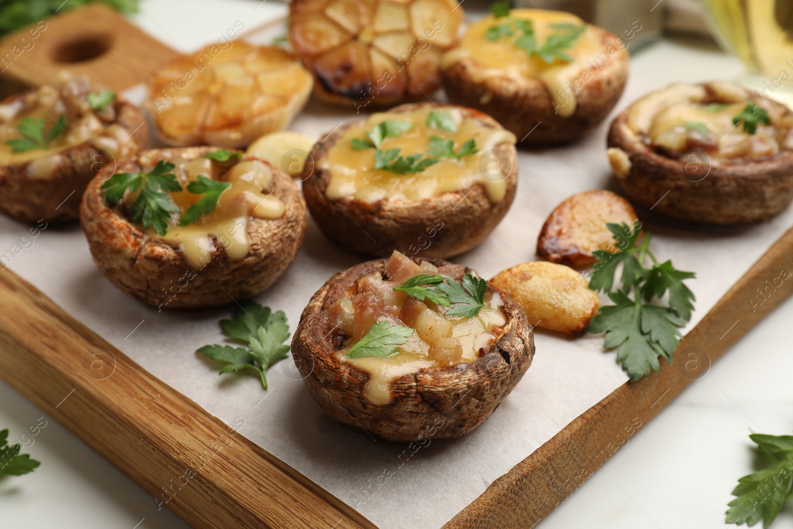 Delicious stuffed mushrooms with melted cheese, garlic and parsley on white table, closeup Photo of Delicious stuffed mushrooms with melted cheese, garlic and parsley on white table, closeup