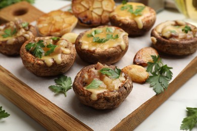 Photo of Delicious stuffed mushrooms with melted cheese, garlic and parsley on white table, closeup