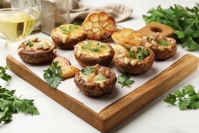 Photo of Delicious stuffed mushrooms with melted cheese, garlic and parsley on white table, closeup