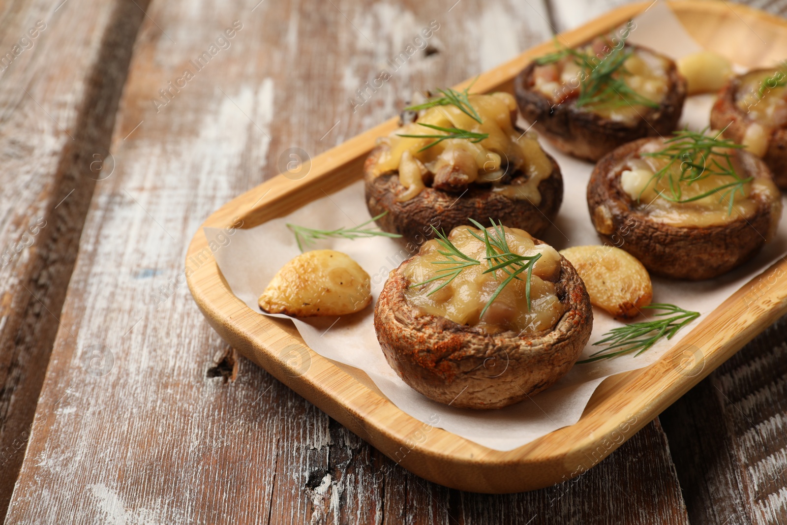 Delicious stuffed mushrooms with melted cheese, garlic and dill on color wooden table, closeup Photo of Delicious stuffed mushrooms with melted cheese, garlic and dill on color wooden table, closeup