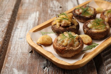Photo of Delicious stuffed mushrooms with melted cheese, garlic and dill on color wooden table, closeup