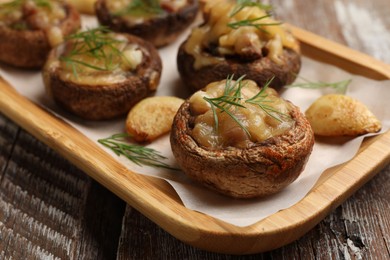 Photo of Delicious stuffed mushrooms with melted cheese, garlic and dill on color wooden table, closeup