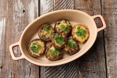 Photo of Delicious stuffed mushrooms with melted cheese and parsley in baking dish on color wooden table, top view