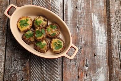 Photo of Delicious stuffed mushrooms with melted cheese and parsley in baking dish on color wooden table, top view. Space for text