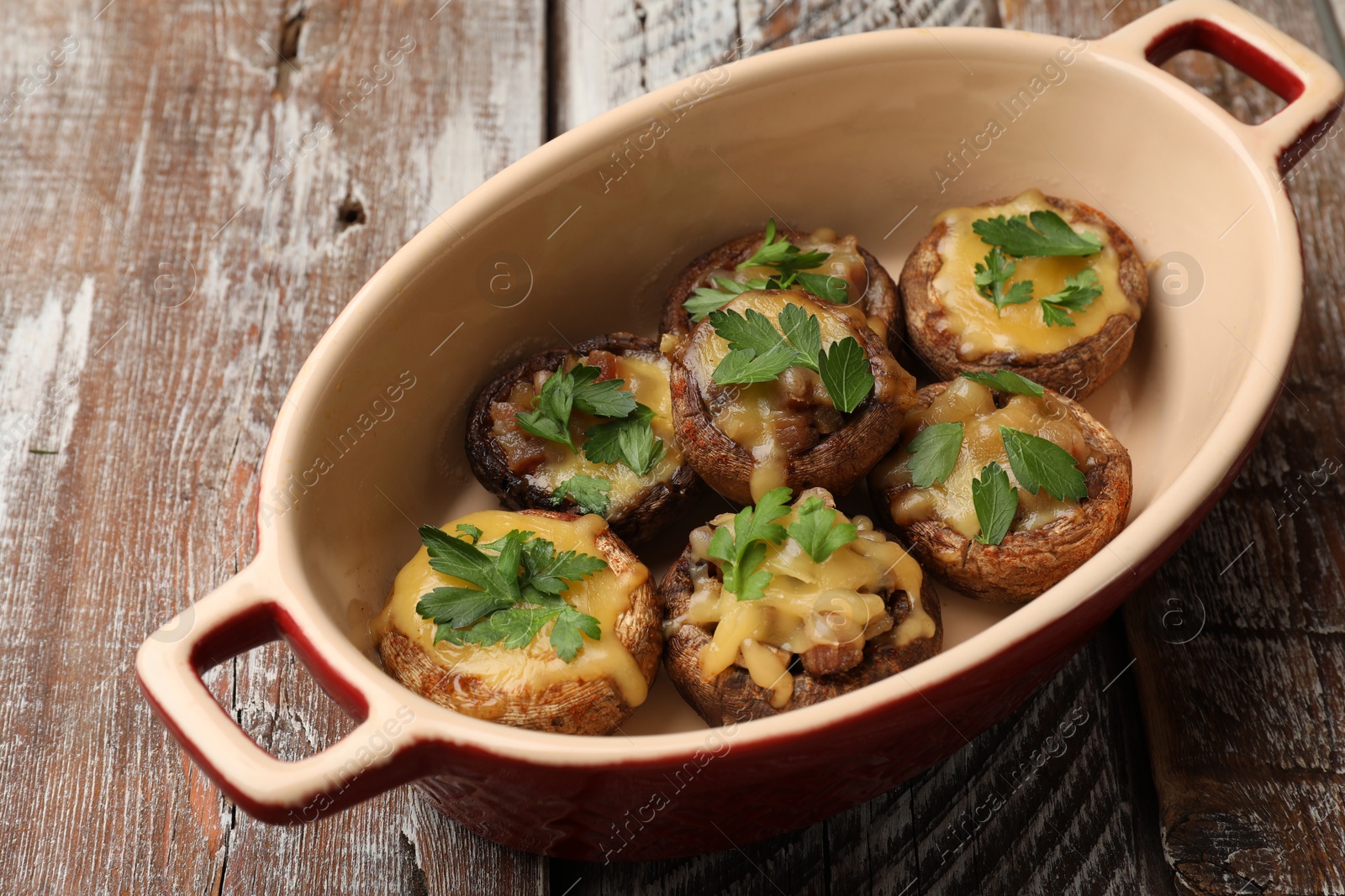 Delicious stuffed mushrooms with melted cheese and parsley in baking dish on color wooden table, closeup Photo of Delicious stuffed mushrooms with melted cheese and parsley in baking dish on color wooden table, closeup