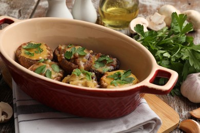 Photo of Delicious stuffed mushrooms with melted cheese and parsley in baking dish on color wooden table, closeup
