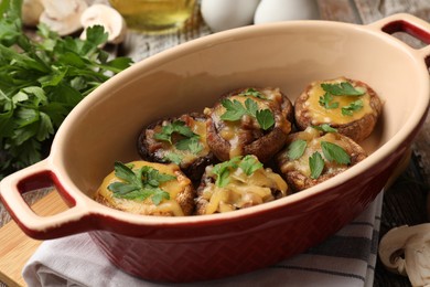 Photo of Delicious stuffed mushrooms with melted cheese and parsley in baking dish on table, closeup