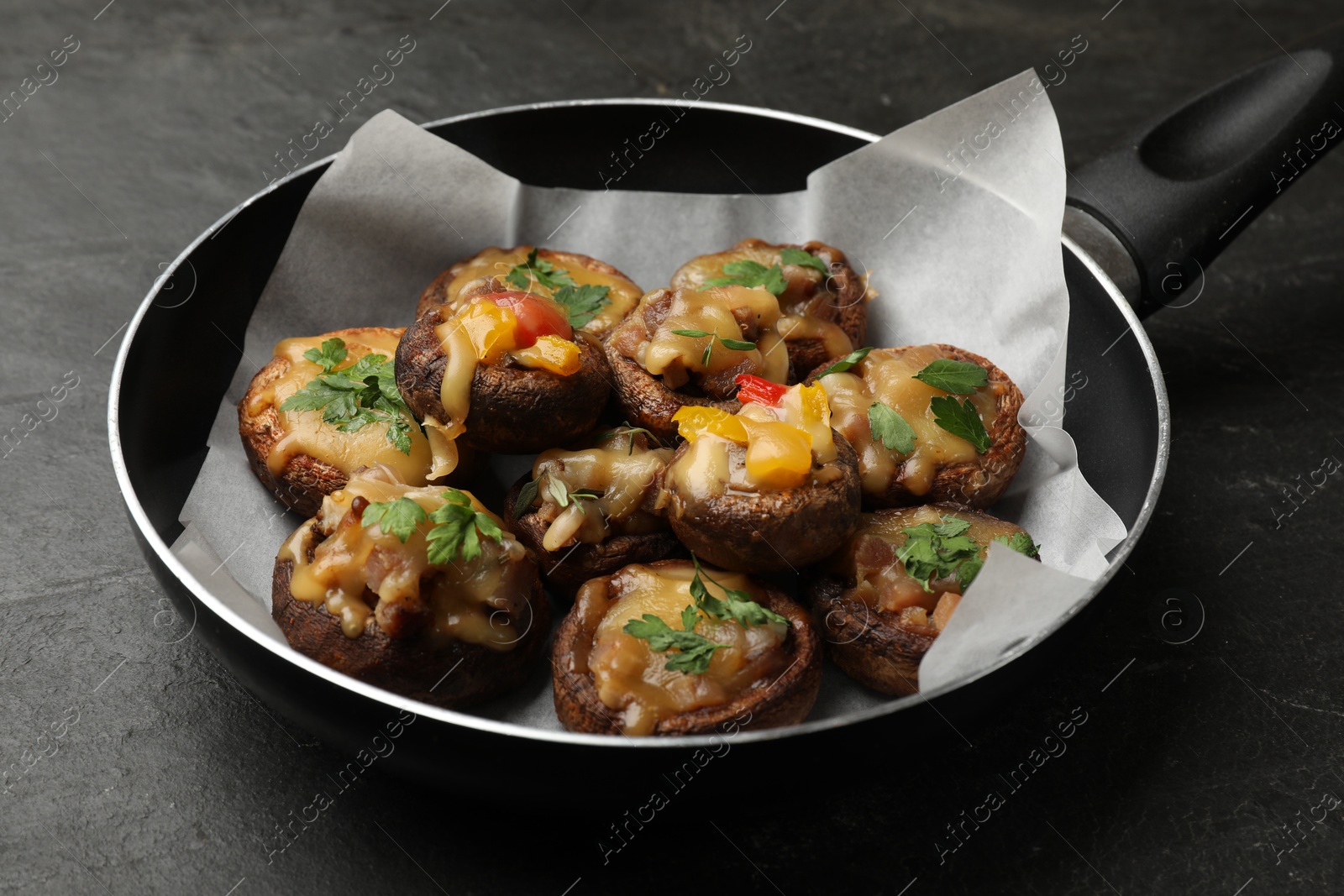 Tasty stuffed mushrooms in frying pan on black table, closeup Photo of Tasty stuffed mushrooms in frying pan on black table, closeup