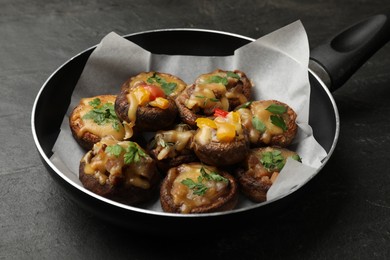 Photo of Tasty stuffed mushrooms in frying pan on black table, closeup