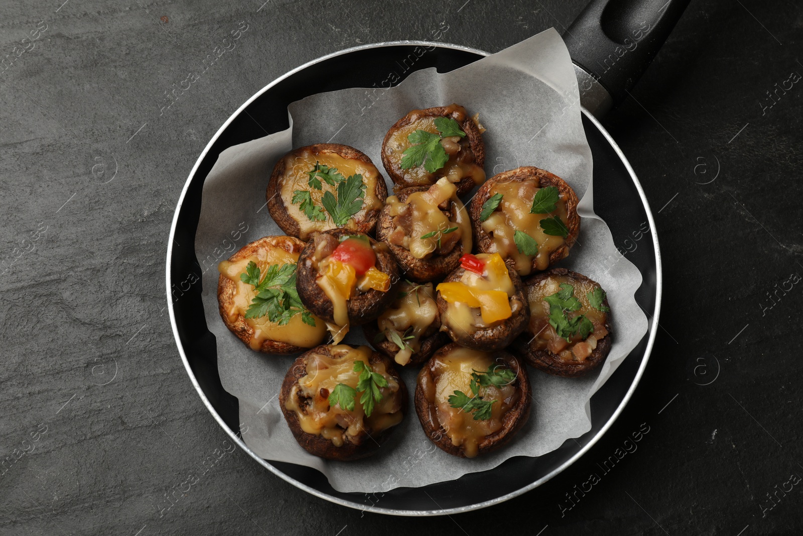 Photo of Tasty stuffed mushrooms in frying pan on black table, top view