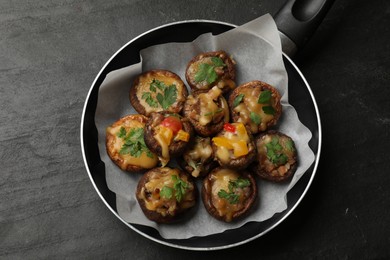 Photo of Tasty stuffed mushrooms in frying pan on black table, top view