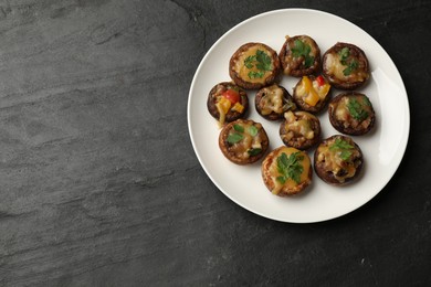 Photo of Tasty stuffed mushrooms on black table, top view. Space for text