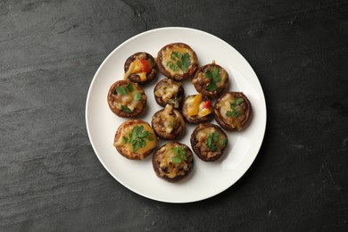 Photo of Tasty stuffed mushrooms on black table, top view