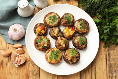 Photo of Tasty stuffed mushrooms and ingredients on wooden table, flat lay