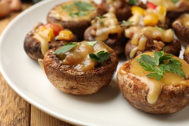 Photo of Tasty stuffed mushrooms on wooden table, closeup
