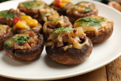 Photo of Tasty stuffed mushrooms on wooden table, closeup