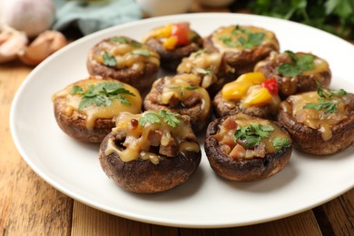 Photo of Tasty stuffed mushrooms on wooden table, closeup