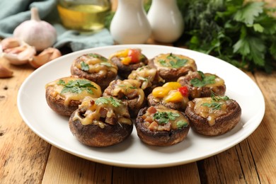 Photo of Tasty stuffed mushrooms and ingredients on wooden table, closeup
