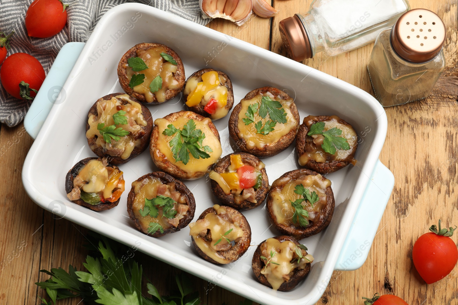 Tasty stuffed mushrooms in baking dish and ingredients on wooden table, flat lay Photo of Tasty stuffed mushrooms in baking dish and ingredients on wooden table, flat lay