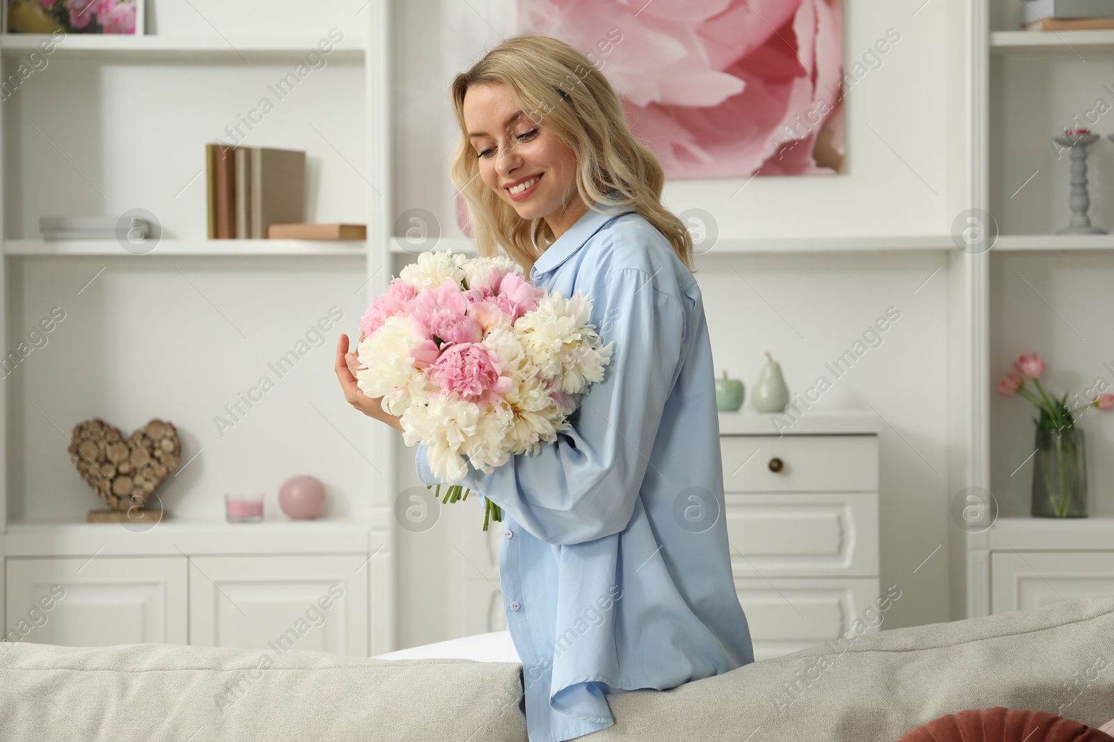 Photo of Happy woman with bouquet of beautiful peonies at home