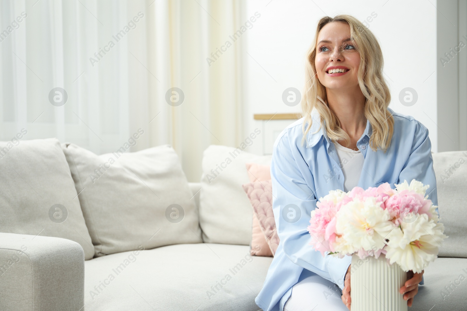 Happy woman with bouquet of beautiful peonies at home, space for text Photo of Happy woman with bouquet of beautiful peonies at home, space for text