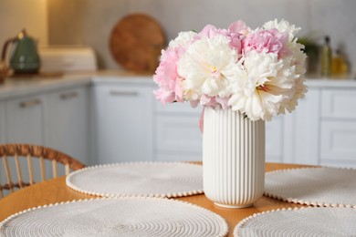 Photo of Beautiful peonies in vase on table indoors, space for text