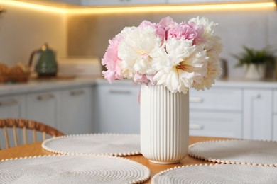 Photo of Beautiful peonies in vase on table indoors, space for text