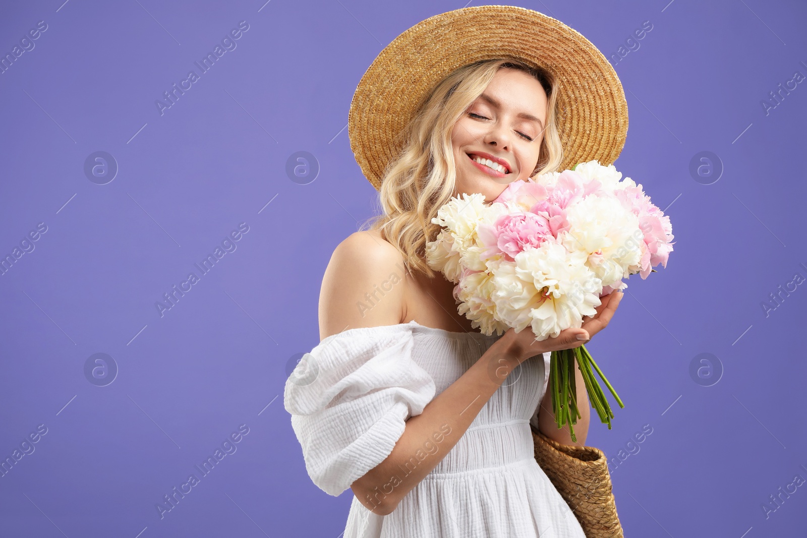 Photo of Happy woman with bouquet of beautiful peonies on purple background, space for text