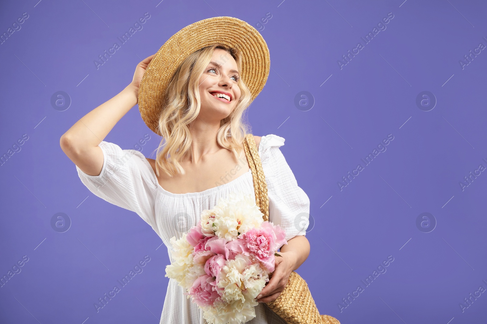 Photo of Happy woman with bouquet of beautiful peonies on purple background, space for text