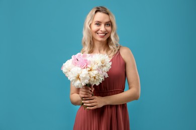 Photo of Happy woman with bouquet of beautiful peonies on light blue background