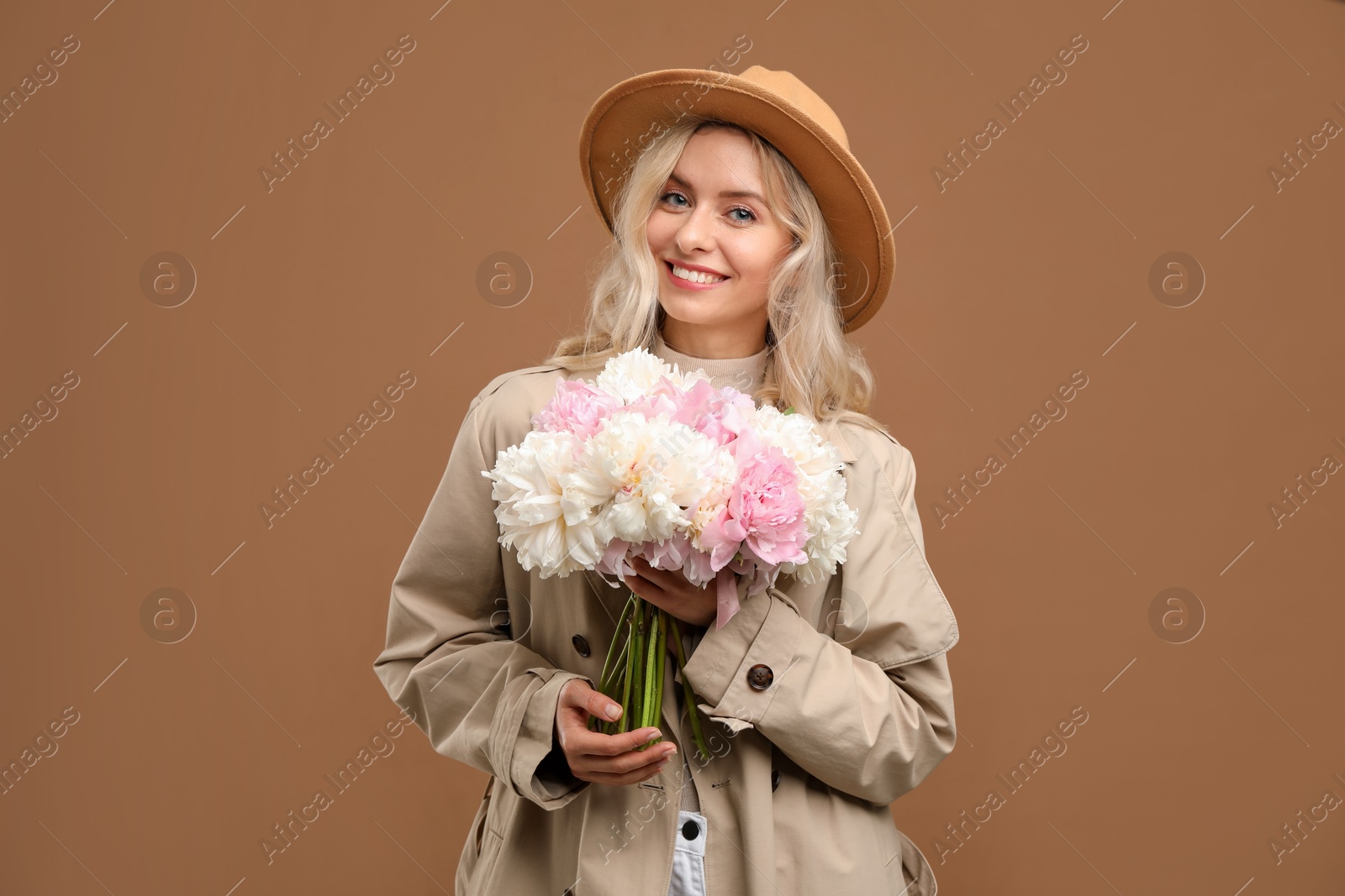 Photo of Happy woman with bouquet of beautiful peonies on brown background