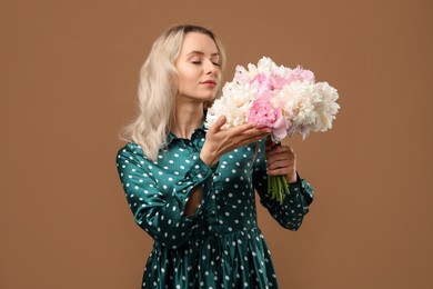 Photo of Woman with bouquet of beautiful peonies on brown background