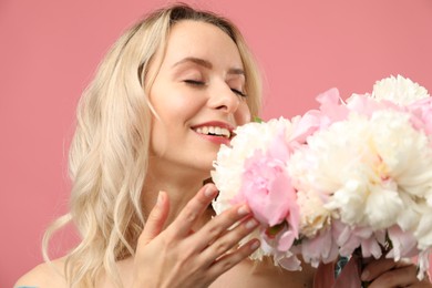 Photo of Happy woman with bouquet of beautiful peonies on pink background
