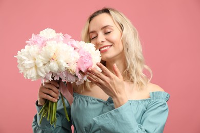 Photo of Happy woman with bouquet of beautiful peonies on pink background