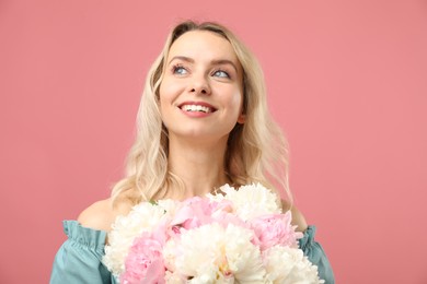 Photo of Happy woman with bouquet of beautiful peonies on pink background