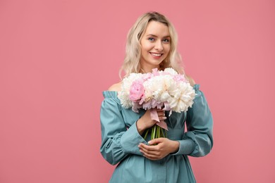 Photo of Happy woman with bouquet of beautiful peonies on pink background