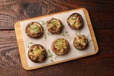 Photo of Delicious stuffed mushrooms with melted cheese and thyme on wooden table, top view