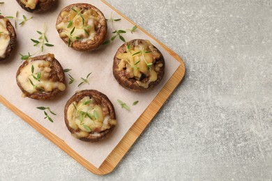 Photo of Delicious stuffed mushrooms with melted cheese and thyme on grey textured table, top view. Space for text