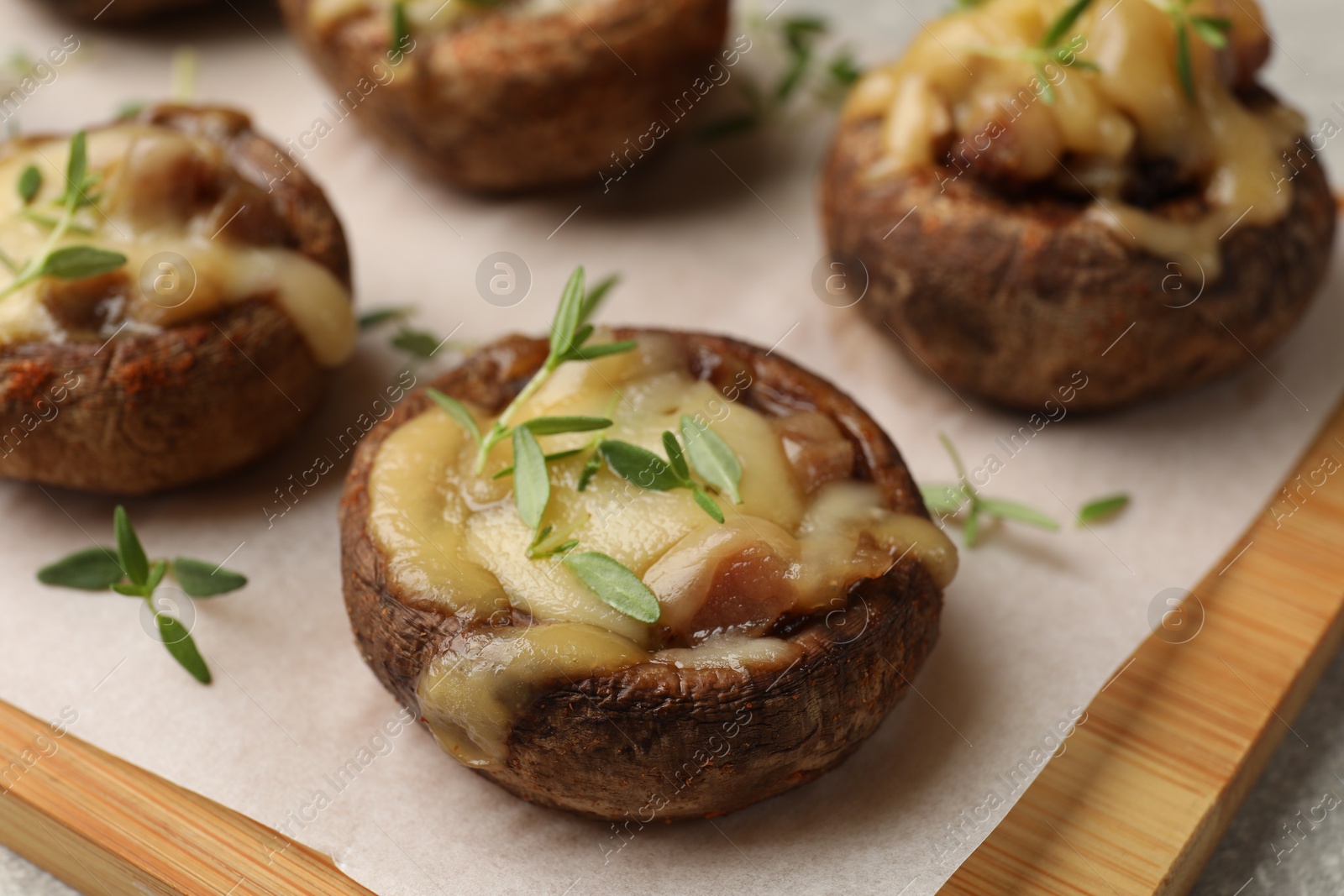 Delicious stuffed mushrooms with melted cheese and thyme on grey table, closeup Photo of Delicious stuffed mushrooms with melted cheese and thyme on grey table, closeup