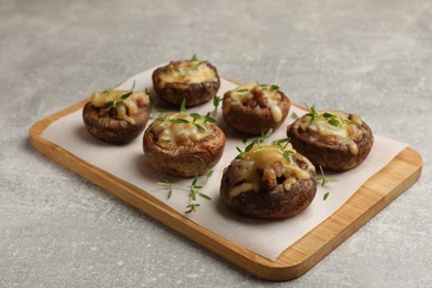 Photo of Delicious stuffed mushrooms with melted cheese and thyme on grey textured table, closeup