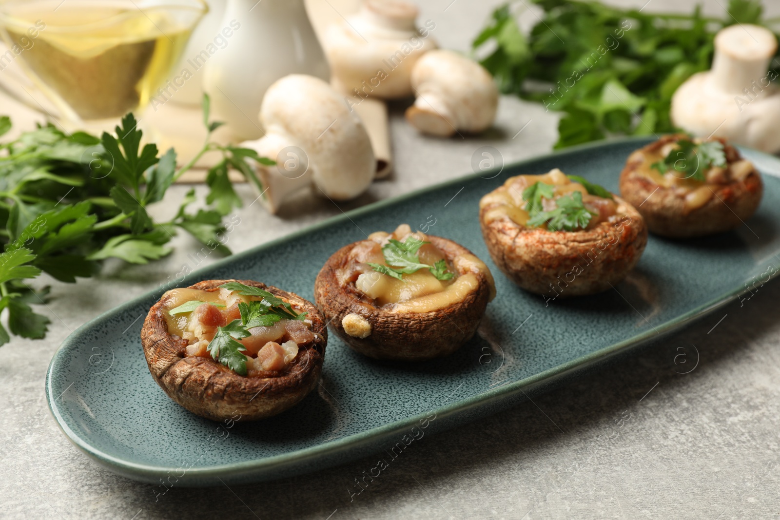 Delicious stuffed mushrooms with melted cheese and parsley on grey textured table, closeup Photo of Delicious stuffed mushrooms with melted cheese and parsley on grey textured table, closeup