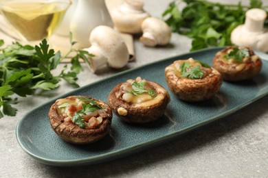 Photo of Delicious stuffed mushrooms with melted cheese and parsley on grey textured table, closeup